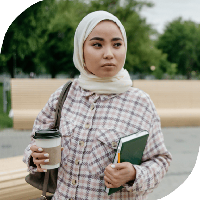 Woman wearing hijab with coffee and notebook